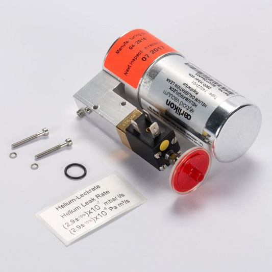 The TL 7 Helium Leak Tester Kit by Leybold North America, including a "Helium Leak Test" canister, metal/plastic apparatus, two screws, O-ring, and leak rate spec card, lies neatly on a gray surface for precise assessments.