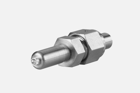 The image features a detailed view of the Test Leak in Cylindric Casing and VCO coupling - 0,5 - 1E-7mbarl/s by Leybold North America. This metallic component boasts a cylindrical design with a hexagonal nut, ideal for vacuum applications. It has a smooth finish and is frequently employed in machinery or plumbing systems for precise leak detection. The backdrop is a plain gray.