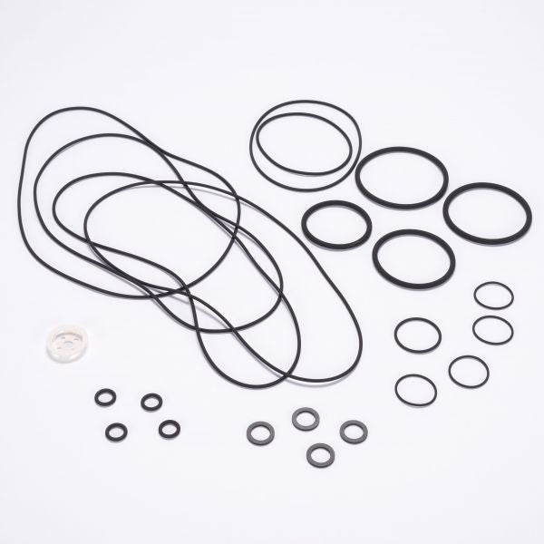The Seal Kit RUVAC WS/WSU 501 - BR2 from Leybold North America features an assortment of black rubber O-rings and belts of various sizes arranged on a white surface, with a single transparent ring among them. The O-rings and belts come in circular and elliptical shapes.