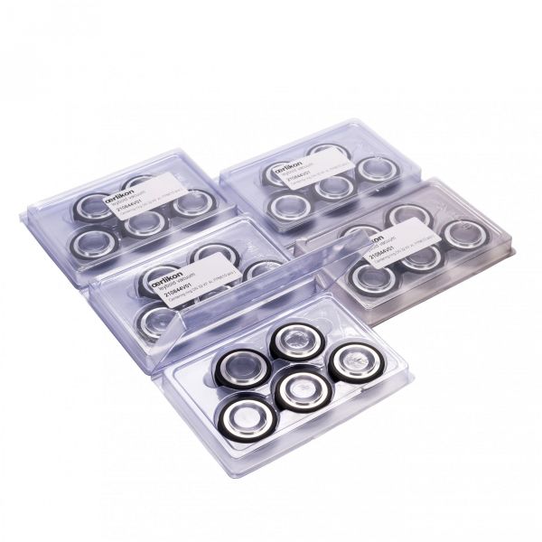 Clear plastic cases hold sets of Leybold North America's metal bearings with dark rubber rings for vacuum use, labeled with model numbers. They rest on a smooth white surface, ideal for displaying the Set of Centering Rings DN 32 ISO-KF.