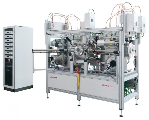 A large, industrial vacuum coating system with a computer-controlled interface is seen on the left. The system features multiple metallic chambers connected by tubes and wires, labeled "UNIVEX Cluster Tool Systems," indicating its brand name "Leybold North America.