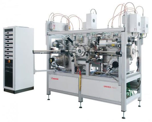 A large, industrial vacuum coating system with a computer-controlled interface is seen on the left. The system features multiple metallic chambers connected by tubes and wires, labeled "UNIVEX Cluster Tool Systems," indicating its brand name "Leybold North America.