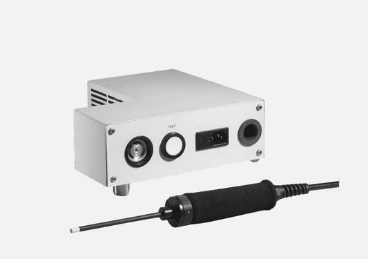 The image shows a close-up of the Leybold North America QUICK-TEST QT 100, an electronic device with a metal casing and various ports on its front panel, including a large circular port and a smaller rectangular one. A black handheld tool connected by a cable is positioned in front of the device.