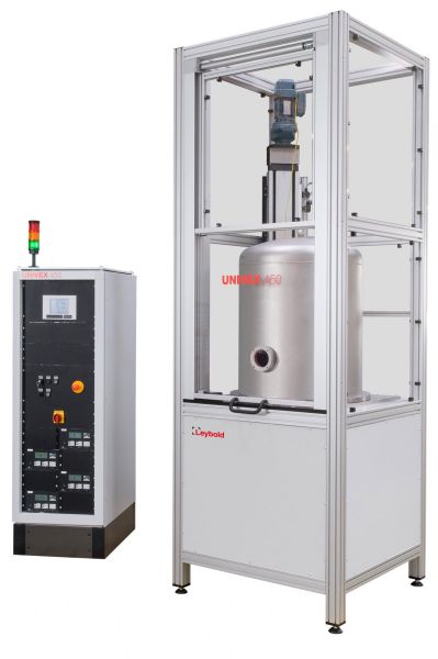 Image of an industrial machine setup. On the left is a tall, white control unit with various buttons, switches, and a display screen. On the right is larger metallic equipment enclosed in a rectangular frame. Both are labeled "Leybold North America Custom Systems.