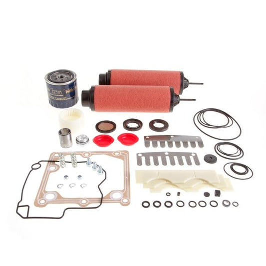 A collection of automotive parts displayed on a white background, including two red cylinder filters, a blue oil filter, gaskets, O-rings, seals, and various metal components. The parts are laid out in an organized manner. Introducing the Repair Kit SV 100 B from Leybold.