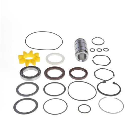 An assortment of mechanical parts is laid out against a white background. The set includes various rubber O-rings, metal rings, a cylindrical bearing, and a yellow star-shaped plastic part. The components vary in size and shape. This is the Sleeve Shaft Seal Kit WA/WAU1001-2001 by Leybold.