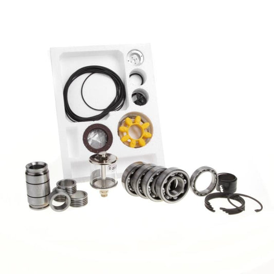 An assortment of mechanical parts from the Major Maintenance Kit WA 1001 by Leybold displayed on a white background, including O-rings, bearings, a mesh filter, and various metal components, some in a white foam organizer. The parts vary in shape and size, with some cylindrical and others circular.