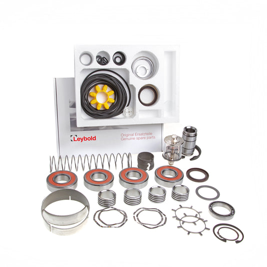 A collection of mechanical parts neatly arranged, including various bearings, springs, and seals. The parts are placed on a white surface with a branded booklet in the background labeled "Leybold Major Maintenance Kit WAU 2001 Genuine spare parts.