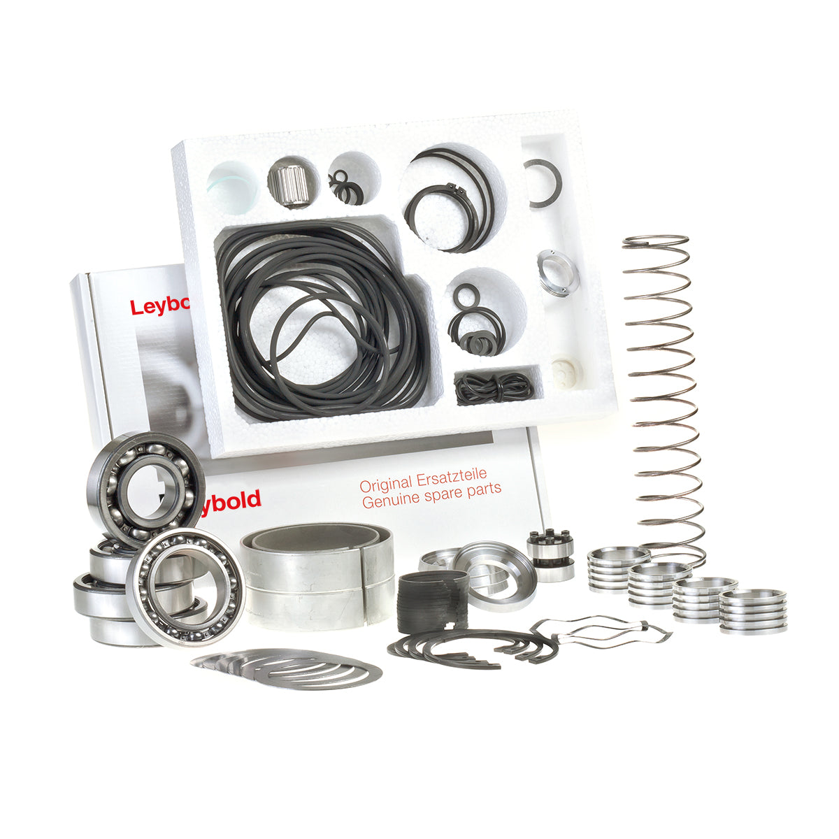 An assortment of genuine Leybold spare parts is displayed, including bearings, seals, springs, and various metallic components. The Major Maintenance Kit WSU 2001 by Leybold is organized in trays and some parts are arranged in front, illustrating the variety of replacement parts available.